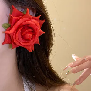 Primo piano di un orecchino a forma di rosa in tessuto rosso con gocce d'acqua simulate