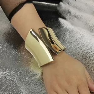 Detailed close-up showing the sleek polished finish of a wide asymmetrical gold metal cuff