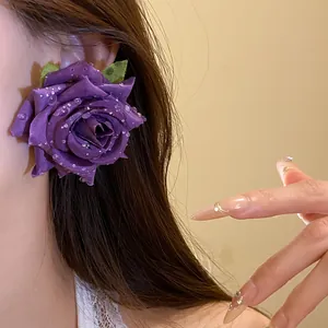 Primo piano dettagliato di eleganti orecchini a rosa in tessuto viola con rugiada