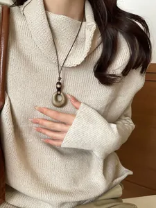 Close-up of a retro wooden semi-circular pendant necklace on a beige knit sweater.