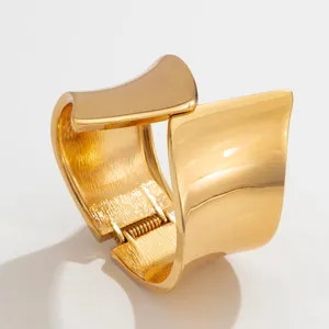 Detailed close-up shot of a wide asymmetric gold-plated metal cuff bracelet with a hinge