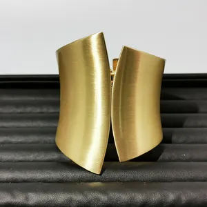 Detail view of a luxury golden wide cuff bracelet with elegant brushed metal finish