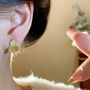 Detailed shot of gold-plated gourd stud earrings featuring sparkling zircon inlay on ear
