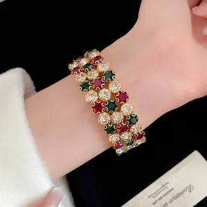 Dettaglio di un elegante bracciale vintage a tre strati con cristalli rossi, verdi e trasparenti