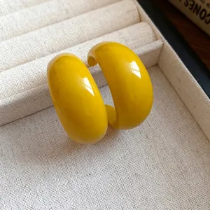 Orecchini a cerchio a forma di C in resina gialla con perni in argento su vassoio