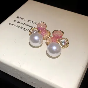 Close-up macro view of luxury white pearl earrings with pink and clear crystal clusters.