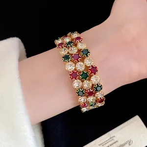 Primo piano di un bracciale vintage in oro a tre file con cristalli rossi e verdi