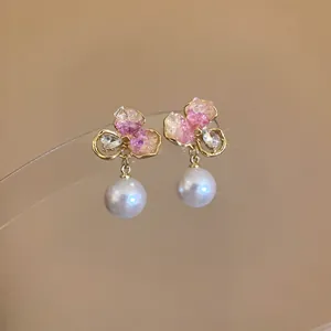 Close-up of elegant floral earrings with pink crystals and dangling pearls