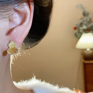 Detailed view of a gold-plated gourd stud earring with zirconia on a model's ear.