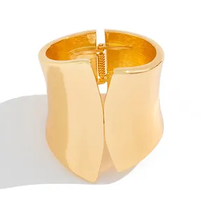 Detail view of wide asymmetric gold-plated metal cuff bracelet with spring hinge.