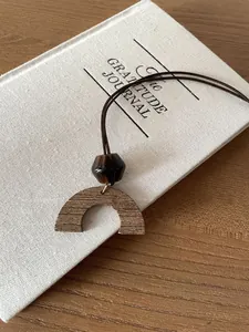 Detailed macro shot of the retro wooden semi-circle pendant and cord necklace.