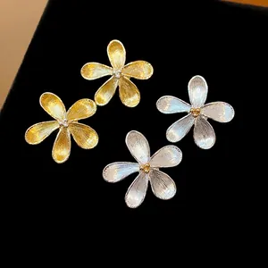Primer plano de elegantes pendientes de flor con acabados texturizados en oro y plata