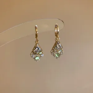 Detail showing diamond-shaped dangle earrings with clear and green rhinestones
