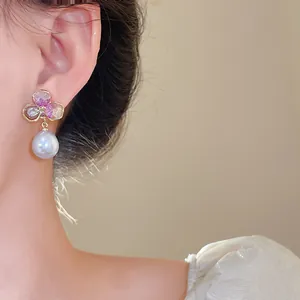 Detailed close-up view of elegant flower pearl drop earrings on an Asian model's ear