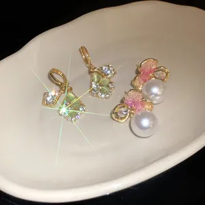 Close-up of diamond-encrusted rhombus ear buckles and pink flower pearl earrings