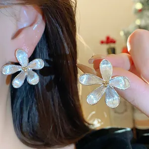 Vista detallada de elegantes pendientes de flor de plata con pétalos texturizados