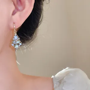 Detailed close-up of elegant rhombic pendant earrings with sparkling diamond inlays