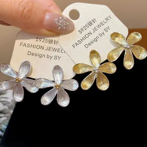 Primer plano detallado de elegantes pendientes de flor en plata y oro en tarjetas