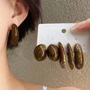 Detailed view of vintage-style marbled acrylic C-shaped stud earrings on a card