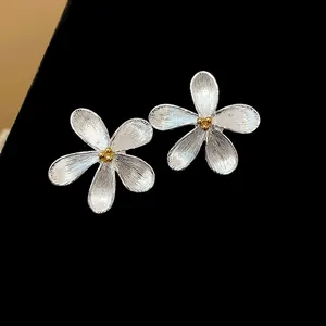 Vista macro detallada de elegantes pendientes de flor plateados con centro dorado