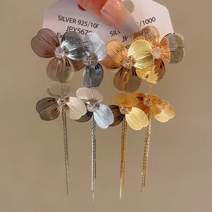 Detailed macro view of gold and silver floral tassel earrings with sparkling cubic zirconia.
