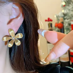 Detalle de cerca de un elegante pendiente de flor dorada con cristal en la oreja