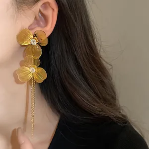 Detailed view of gold flower tassel earrings featuring crystal centers on a model