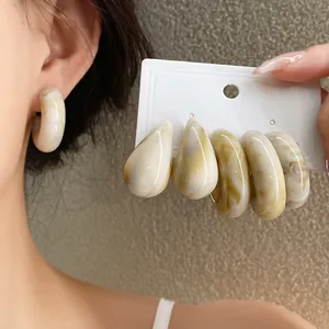 Macro detail of elegant vintage marbled acrylic C-shaped and teardrop earrings jewelry set