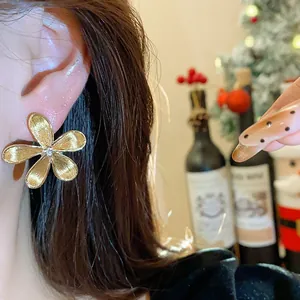 Elegantes pendientes de botón de flor dorada con pétalos de textura fina en la oreja