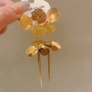 Detailed shot of gold-plated floral earrings featuring long tassels and crystals