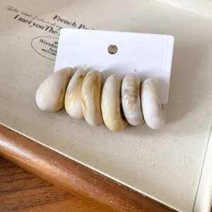 Detail view of vintage acrylic marbled C-shaped stud earrings on white card display