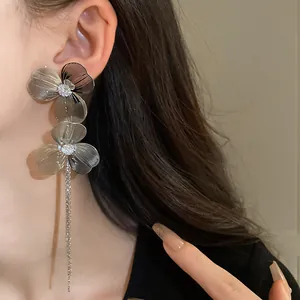 Close-up of elegant silver-toned floral drop earrings with long tassels on model