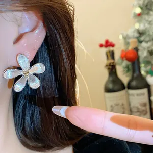 Primer plano de un elegante pendiente de flor plateado usado en una oreja femenina.