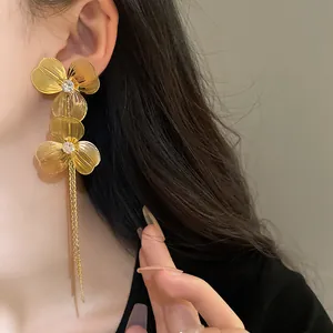 Detailed close-up of elegant gold-plated flower earrings with long chain tassels on a model