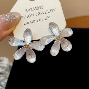 Vista detallada de pendientes de flor de plata con agujas S925 en tarjeta de joyería