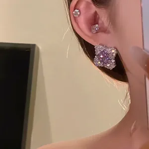 Close-up detail of sparkling lavender zirconia rhombus stud earrings worn on an earlobe