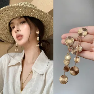 Detailed view of gold textured round tassel earrings on model and close-up product