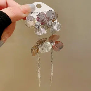 Close-up of gold-plated flower tassel earrings with sparkling stones.
