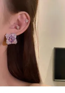 Close-up of sparkling purple zirconia rhombus earrings on ear