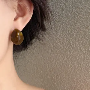 Close-up view of a stylish amber marbled acrylic C-shape earring worn for a retro minimalist look