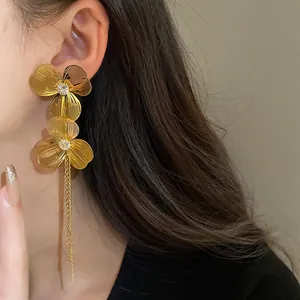 Close-up of elegant gold plated flower tassel earrings worn on a model with long hair