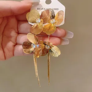 Detailed view of luxury gold-plated flower earrings with sparkling crystal and elegant tassels