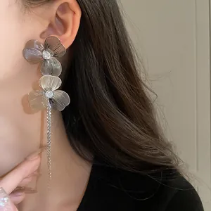 Close-up view of elegant silver floral tassel earrings worn by a stylish model