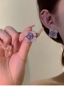 Detail showing elegant purple zircon rhombus stud earrings with a shiny crystal halo