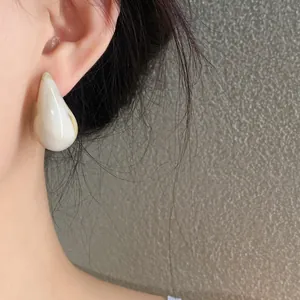 Close-up of white marble acrylic teardrop earring worn on ear, vintage elegant style