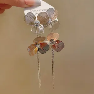 Detailed macro view of gold-plated flower tassel earrings with sparkling rhinestone centers