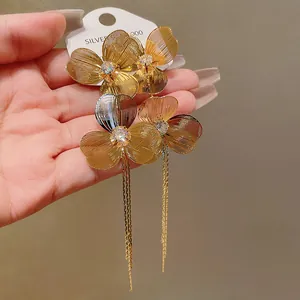 Close-up of gold-plated flower tassel earrings with crystal center
