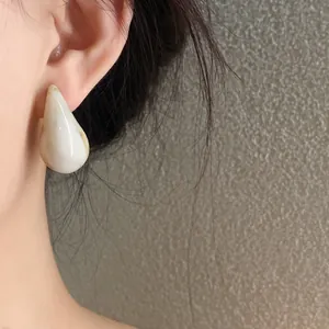 Close-up of marbled acrylic teardrop earrings worn on ear showing smooth texture