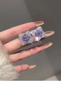 Detailed macro view of rhombus stud earrings with purple center stone and zircon halo