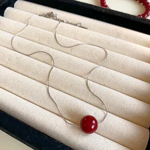 Close-up of elegant red pearl necklace on a cream velvet jewelry display tray